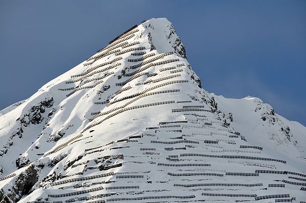 Zahlreiche Lawinenverbauungen aus Stahl stehen an der steilen, schneebedeckten Flanke des Schiahorns