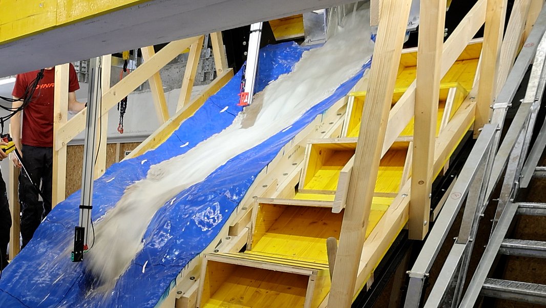 Blaues, spiegelverkehrtes Modell der Region von Blatten. Von oben kommt ein Matschgemisch den künstlichen Hang herunter.
