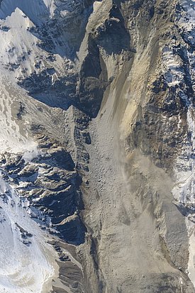 Das Bild zeigt eine Aufnahme des oberen Teils des Kleinen Nesthorns im Lötschentals nach dem Felssturz. Die Felsen sind schneebedeckt und der Felssturz ist wie eine braune Schneise. 
