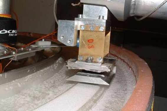 Abb. 1: Eine Materialprobe wird auf die rotierende Eisunterlage gedrückt (Foto: Archiv SLF).