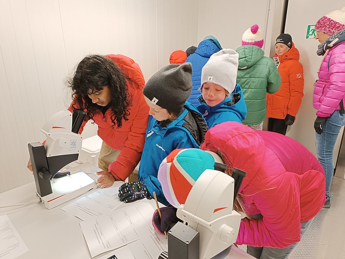 Bei -20 Grad Celsius betrachteten die jungen Besucherinnen und Besucher Schneekristalle mit der Lupe. (Foto: Sara Niedermann / SLF)(jpg, 3 MB)