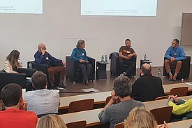 Fünf Personen sitzen halbkreisförmig in Sesseln.