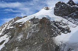 Felsiger Berg mit Schneefeldern unter blauem Himmel
