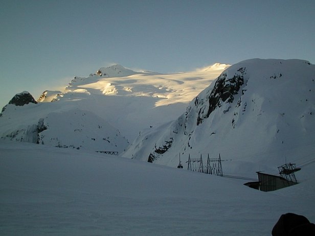 Abb. 26: Basodino, 21.2.2001. Der Nordwind löst am Alpenhauptkamm die Wolken auf und erzeugt grosse Schneefahnen Richtung Süden. Trotz des vielen Schnees sind die Spaltenbereiche am Basodinogletscher gut erkennbar. Das Bild ist von der Verleichsstation Robiei (1890 m) aufgenommen. Dort lag an diesem Tag 280 cm (Mittelwert 161 cm) gut verfestigter Schnee mit durchschnittlich 350 kg/m3 Dichte. Der Wasserwert betrug 1000 mm. Der Aufbau der Schneedecke war zu diesem Zeitpunkt viel stabiler im Vergleich zum ebenfalls meist Süd-beeinflussten Val Müstair (Foto: SLF / T. Wiesinger).