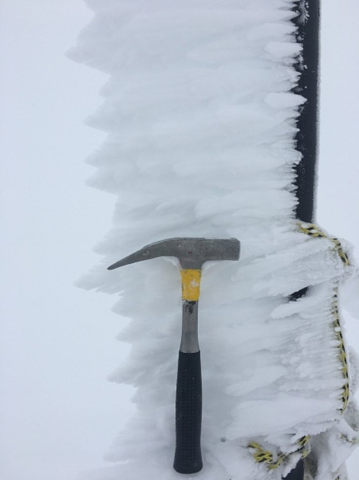 An dieser Eisenstange bildete sich ein "Rauheisbart". Der Wind wehte im Bild von links nach rechts. Dabei froren unterkühlte Wassertröpchen an der kalten Eisenstange an. Weitere Wassertropfen lagerten sich am schon bestehenden Rauheis an und der "Bart" wuchs von rechts nach links gegen die Windrichtung (Foto: M. Hepting, 29.07.2017).