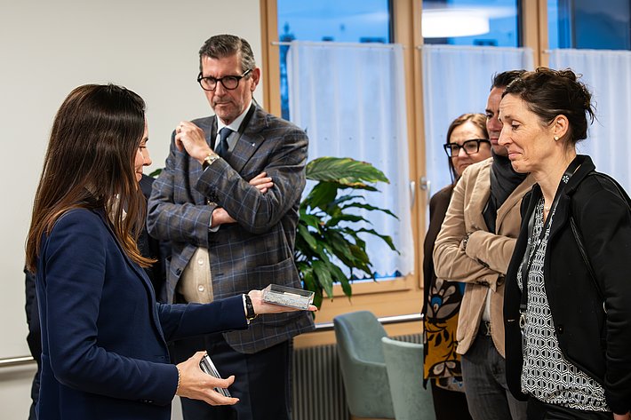 Le président de la SUPSI Giovanni Merlini et la mathématicienne et ancienne directrice de la taskforce COVID Tanja Stadler écoutent avec attention la chercheuse de l'EMPA Nathalie Casas expliquer comment elle compte extraire de l'atmosphère le CO<sub>2</sub>, matière première de l'avenir. (Photo : Luzia Schär)